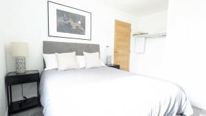 1 dormitorio blanco con 1 cama grande con almohadas blancas en Modern 2 Bed Apt - 15 Mins to Birmingham Centre, en Birmingham