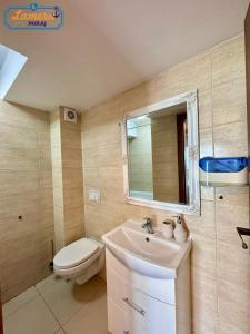 een badkamer met een wastafel, een toilet en een spiegel bij Lamera-Miraj sea view in Mamaia