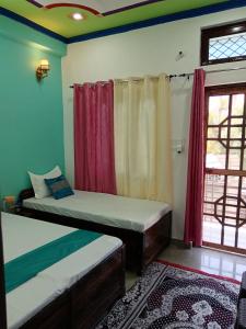 een slaapkamer met 2 bedden, een raam en een tapijt bij Hotel Tejas in Gupta Kāshi