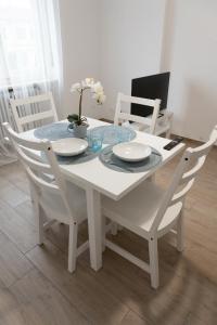 uma mesa de jantar branca com cadeiras brancas, uma mesa branca e uma espreguiçadeira em Casa Zaffiro em Savigliano