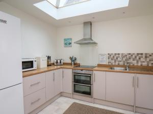 a kitchen with white cabinets and a skylight at Ty-Clyd in New Quay