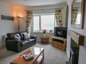 a living room with a leather couch and a television at Ty-Clyd in New Quay