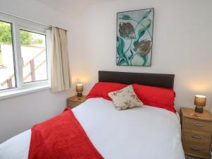 a bedroom with a red and white bed and a window at Ty-Clyd in New Quay