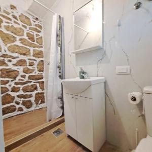 bagno con lavandino e parete in pietra di Unique Apartment Centar a Podgorica