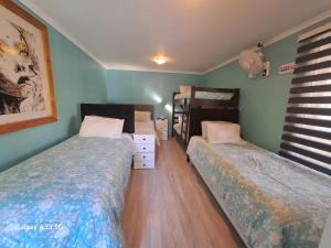 two beds in a bedroom with green walls and wooden floors at HOSTAL EL AROMO☆ in Chillán