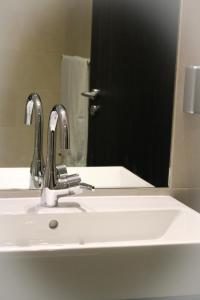 a bathroom with a sink and a mirror with a door at Freimühle Hotel-Restaurant in Girod