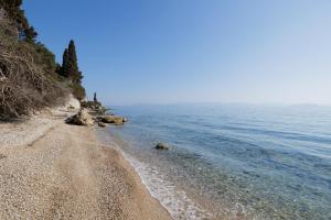 a beach with a rocky shoreline next to the water at Nisos Villa Emerald in Kornáta