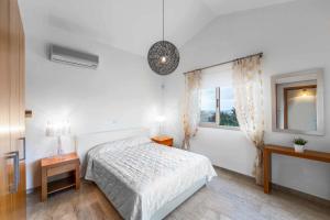 a white bedroom with a bed and a window at Villa Paralia in Polis Chrysochous +20 photos