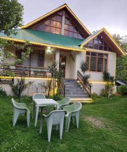 une maison avec une table et des chaises dans la cour dans l'établissement Vamika Cottages, à Manali