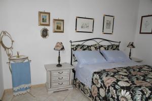 a bedroom with a bed and a nightstand and pictures on the wall at La Mimosa in Bolgheri