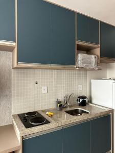 a kitchen with blue cabinets and a sink at Lindo Studio em frente a praia in Salvador