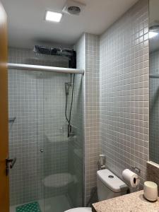a bathroom with a glass shower with a toilet at Lindo Studio em frente a praia in Salvador