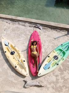 a woman sitting in a pink kayak next to three surfboards at el arca in Cartagena de Indias