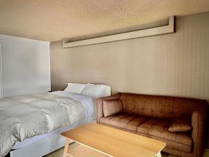 a bedroom with a bed and a couch and a table at Stay`sOTARU in Otaru