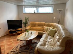 sala de estar con sofá de cuero y TV en Ferienwohnung Behrens en Celle