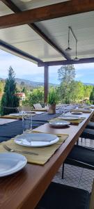 a long wooden table with plates and glasses on it at Quinta do Rio Alva and Glamping Lodges in Mouronho