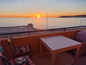 balkon ze stołem, krzesłami i zachodem słońca w obiekcie Appt T3 VUE MER w mieście Six-Fours-les-Plages