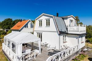 卡爾斯克魯納的住宿－Nice house with a panoramic view of the sea on beautiful Hasslo outside Karlskrona，白色的房子,设有门廊和甲板