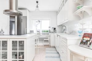 een witte keuken met witte werkbladen en witte kasten bij Nice house with a panoramic view of the sea on beautiful Hasslo outside Karlskrona in Karlskrona