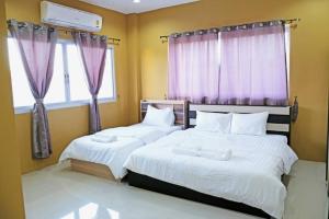 two beds in a bedroom with purple curtains at The Bua Boutique Resort in Ban Huai Krabok