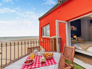 a red house with a table with food on the balcony at 3 Bed in Tenby 60757 in Tenby