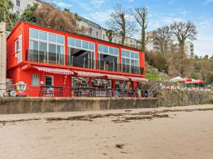 a red building with tables and chairs on the beach at 3 Bed in Tenby 60757 in Tenby