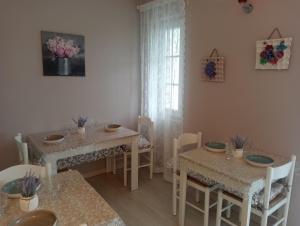 un comedor con 2 mesas y sillas y una ventana en Villa Rosetta wellnes relax, en Scrutto