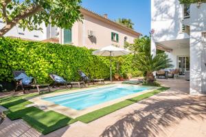 einen Pool in einem Garten mit Stühlen und einem Sonnenschirm in der Unterkunft Villa Mar - Can Bujosa in Palma de Mallorca
