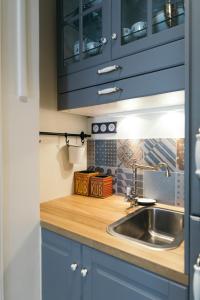 eine Küche mit blauen Schränken und einer Spüle in der Unterkunft Chez Pépé Merle - Chambres d'hôtes dans le quartier du Père Lachaise in Paris + 55 Fotos