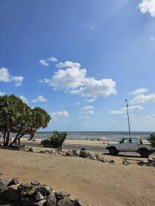 biały samochód zaparkowany na plaży w pobliżu oceanu w obiekcie BRISE DE MER : 2 ROOM / CHAMBRES w mieście Dżibuti