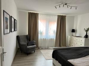 a bedroom with a bed and a chair and a window at Ferienwohnung Altstadtblick- zentral am Hafen & Otto Huus in Emden