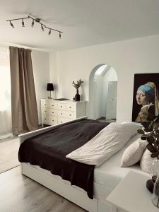 a white bedroom with a large bed and a dresser at Ferienwohnung Altstadtblick in Emden