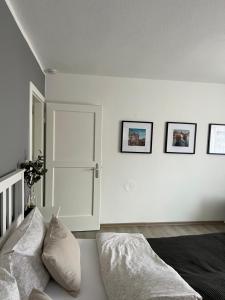 a white room with a bed and three pictures on the wall at Ferienwohnung Altstadtblick in Emden