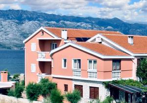 duży różowy budynek z górami w tle w obiekcie Cosy Apartment in Ražanac 34 m² + View w Ražancu