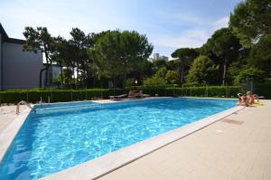 a large blue swimming pool with people sitting around it at Appartamenti Erica in Bibione