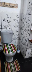 a bathroom with a toilet with striped mats on the floor at Eco Hostel Lunar in Soure