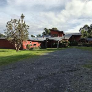 a red barn with a driveway in front of it at Lodge El Taique in Puyehue