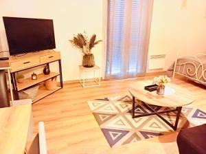 a living room with a television and a table at Le Cosy Home in Oyonnax