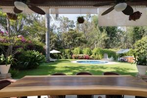 una mesa de madera frente a un patio con piscina en Welcome to Villa Cristy 3-BR 3 5-WC in the La Floresta area, en Ajijic