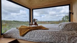łóżko w pokoju z dużym oknem w obiekcie Tiny House au milieu des Vignes w mieście Arbis