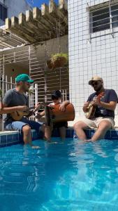 three men sitting in a swimming pool playing guitar at Casa Olinda in Olinda