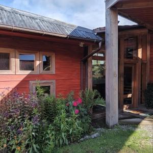 een rood huis met bloemen ervoor bij Lodge El Taique in Puyehue