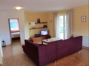 ホークジールにあるFerienwohnungen Tengeのリビングルーム(紫色のソファ、テレビ付)