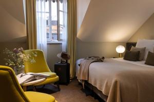ジュネーヴにあるHotel D Genevaのベッド1台、椅子、窓が備わる客室です。