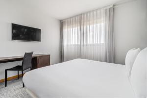 マドリードにあるExe Convention Plaza Madridの白いベッドとデスクが備わるホテルルームです。