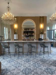 a bar with four stools in a room at Grand Hôtel "Château de Sully" - Piscine & Spa in Bayeux