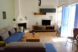 een woonkamer met een bank en een tv bij Vori`s blue door country house in Vóroi