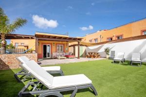 a patio with two lounge chairs and a lawn at Villa del Relax in Corralejo