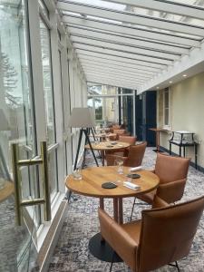 un restaurante con mesas, sillas y ventanas en Grand Hôtel "Château de Sully" - Piscine & Spa, en Bayeux