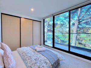 um quarto com uma cama e uma grande janela em Grandeur Innercity Townhouse em Melbourne